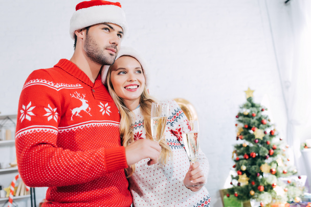 Різдвяна пара тримає келихи шампанського і обіймається вдома
  - Фото, зображення