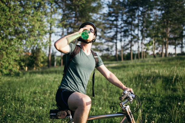 Mountain biker in sunset drinking water - Foto, Bild