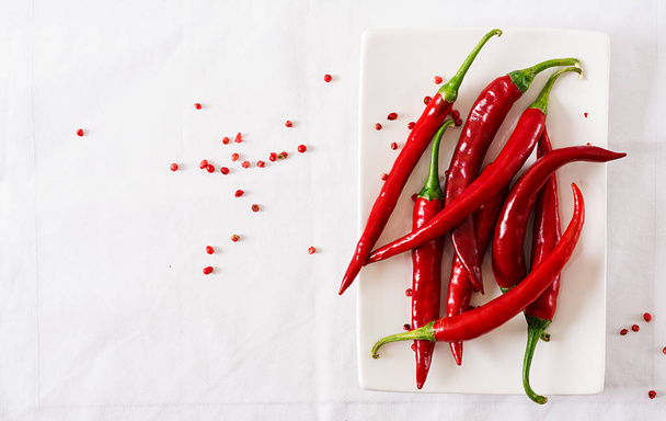 Red hot chili papričky v desce na bílém stole. Pohled shora. Rozložení bytu - Fotografie, Obrázek