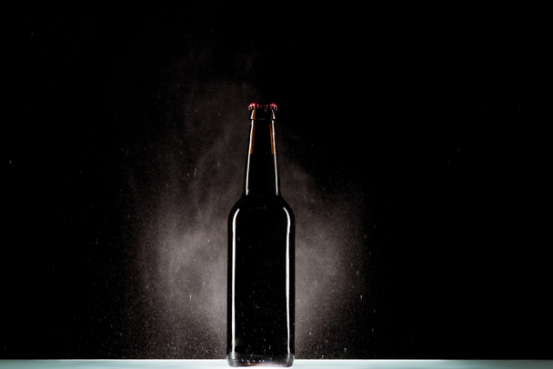 bottiglia di birra scura con spruzzatura di acqua intorno alla superficie su sfondo nero
  - Foto, immagini