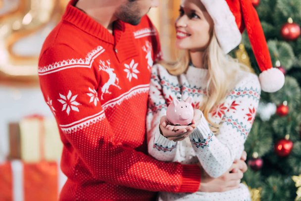 couple dans santa chapeaux tenant tirelire avec billet de banque à la maison le soir de Noël
 - Photo, image