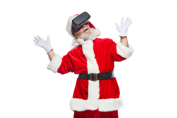 Christmas. Santa Claus in black virtual reality glasses makes gestures with his hands. Surprise, emotion. New technology. Isolated on white background. - Φωτογραφία, εικόνα