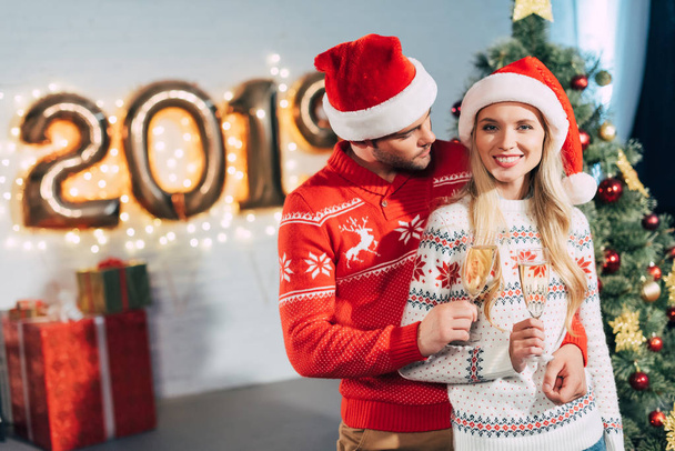 heureux couple chapeaux santa cliquetis avec des verres de champagne et célébrer 2019 nouvelle année
 - Photo, image
