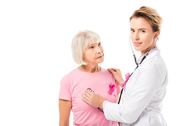 arts met de stethoscoop controle van de gezondheid van de vrouw van de senior en kijken naar camera geïsoleerd op wit, borst kanker concept - Foto, afbeelding