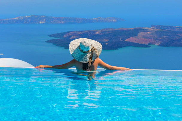 Woman enjoying relaxation in pool and looking at the view in Santorini Greece - Valokuva, kuva