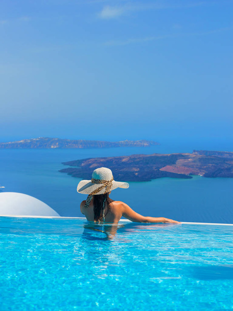 Nainen nauttimassa rentoutumisesta uima-altaassa ja katselemassa näkymää Santorinissa Kreikassa - Valokuva, kuva