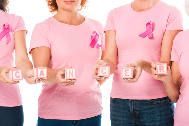 rajattu kuva naisista vaaleanpunaisissa t-paidoissa rintasyöpätietoisuuden nauhoilla pitäen kuutioita, joissa sana syöpä on eristetty valkoisella
 - Valokuva, kuva