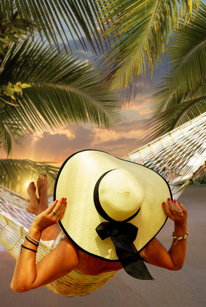 Woman in hat sitting in hammock on the beach. Travel and vacation concept. - Фото, изображение