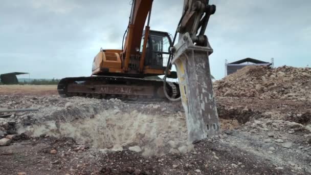Excavator with hydraulic hammer drill at work breaking down earth for construction ground foundation - Footage, Video