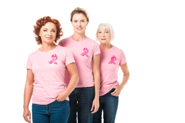 smiling women with pink ribbons standing together and looking at camera isolated on white, breast cancer awareness concept  - Photo, Image