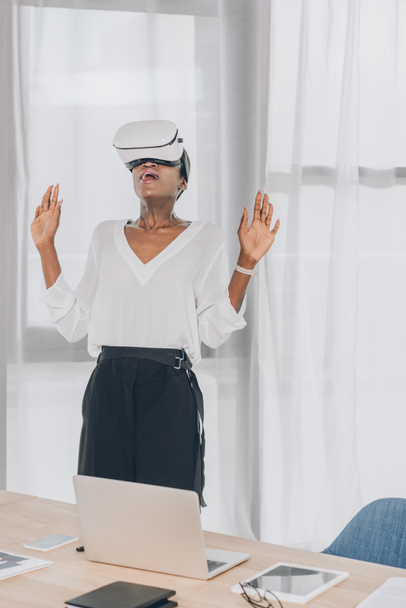 stylish shocked african american businesswoman looking up in virtual reality headset in office - Zdjęcie, obraz