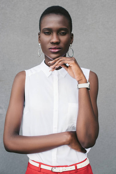 zamyšlený stylové atraktivní africká americká žena odpočívá bradu na straně šedé zdi - Fotografie, Obrázek