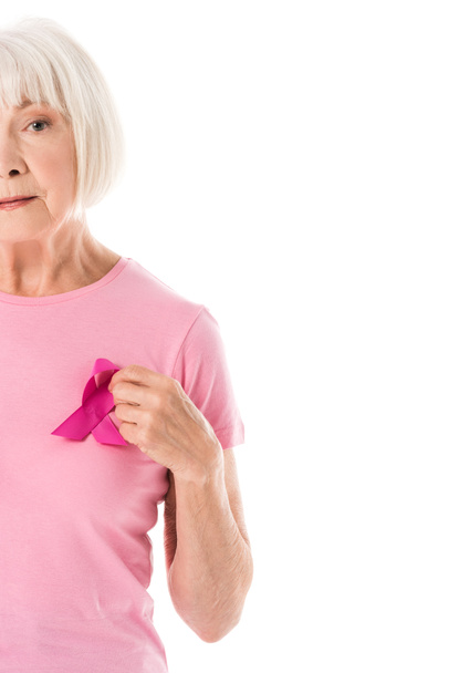Schnappschuss einer Seniorin in rosa T-Shirt mit Brustkrebs-Bewusstseinsband, die isoliert auf weiß in die Kamera blickt - Foto, Bild