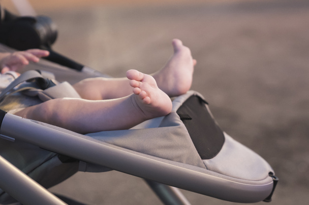 Новорожденный босиком спит в коляске на открытом воздухе
 - Фото, изображение