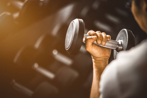 Close up of fit young hand caucasian big muscle in sportswear. Young man holding dumbbell during an exercise class in a gym. Healthy sports lifestyle, Fitness concept. - Photo, Image