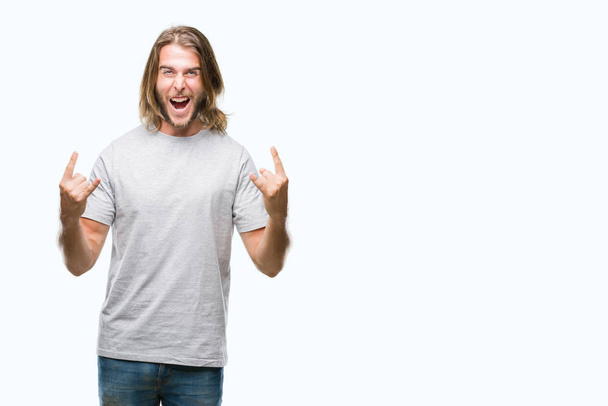 Young handsome man with long hair over isolated background shouting with crazy expression doing rock symbol with hands up. Music star. Heavy concept. - Photo, Image