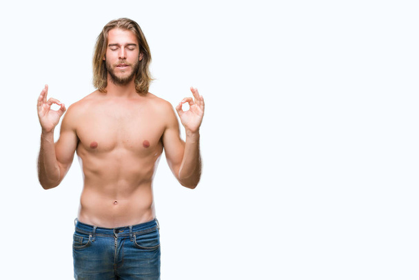 Mladý pohledný muž košili s dlouhými vlasy ukazovat sexy tělo izolované pozadí relaxovat a usmívající se očima uzavřené vede meditační gesta prsty. Koncept jógy. - Fotografie, Obrázek