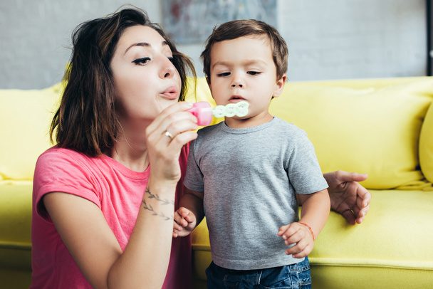 happy mom and little son blowing soap bubbles together at home  - Photo, image