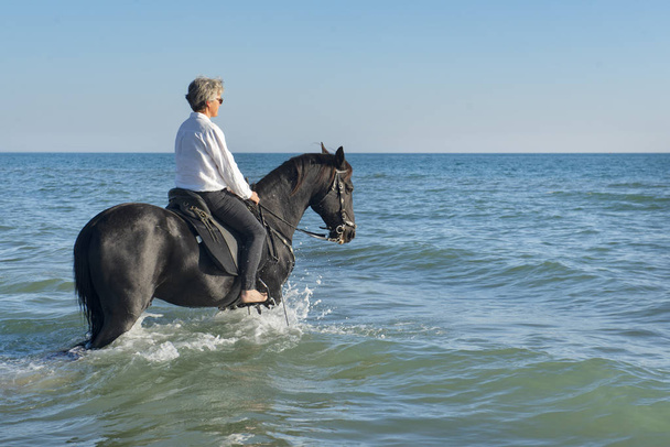  Meisje paardrijden zijn opleiding van haar paard op het strand - Foto, afbeelding