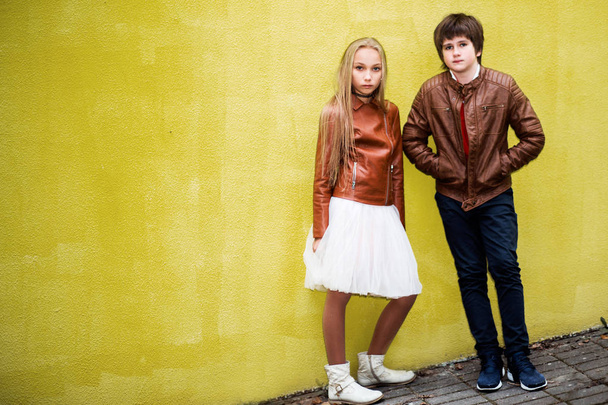 photo of Boy and teen girl posing against a yellow wall background - Foto, immagini