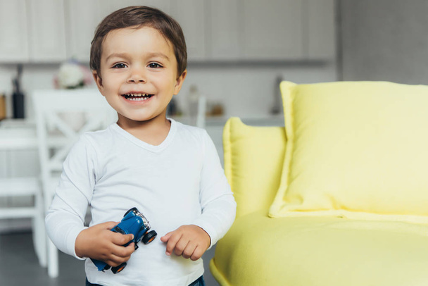 adorable smiling boy holding toy car at home - Foto, Imagem
