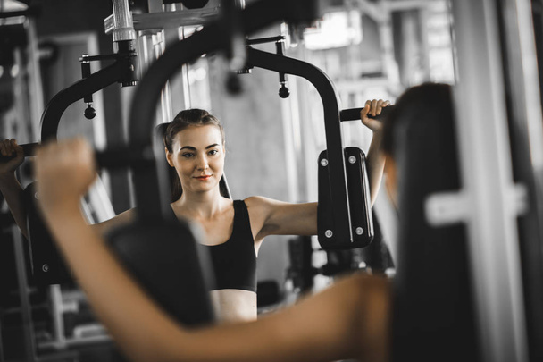 Fit beautiful young woman exercise workout on machine in gym. Gl - 写真・画像