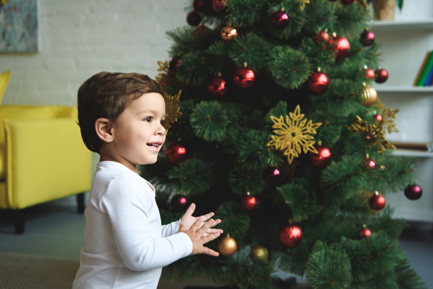 自宅のクリスマス ツリーの近くに愛らしい笑みを浮かべて少年 - 写真・画像