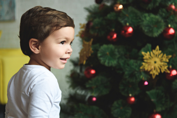happy boy standing near christmas tree at home - Foto, imagen