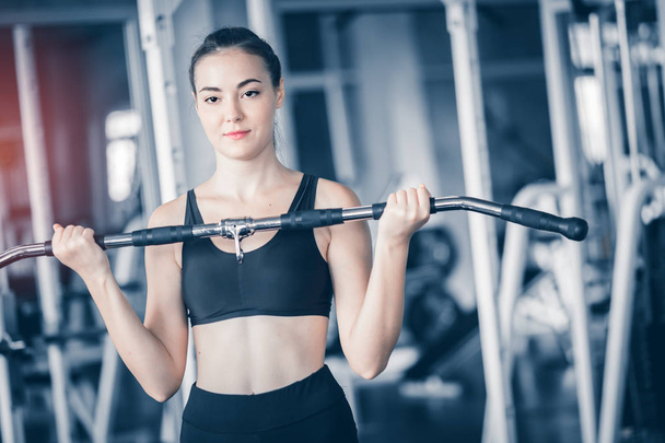 Fit beautiful young woman caucasian posing at the camera in sportswear. Young woman holding dumbbell during an exercise class in a gym. Healthy sports lifestyle, Fitness concept. With copy space. - Foto, Imagem