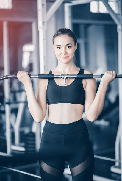 Fit beautiful young woman exercise workout on machine in gym. Glad smiling girl is enjoy with her training process. Concept of fitness, Healthy, Sport, Lifestyle - Foto, afbeelding