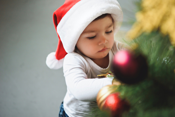 adorable petit garçon en chapeau de Père Noël décorant arbre de Noël
 - Photo, image