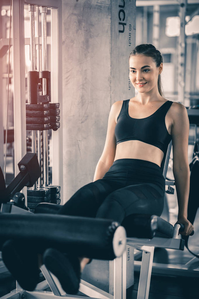 Fit beautiful young woman exercise workout on machine in gym. Glad smiling girl is enjoy with her training process. Concept of fitness, Healthy, Sport, Lifestyle - Фото, зображення