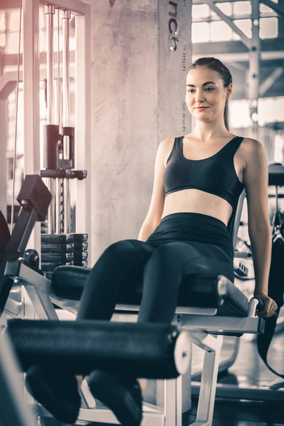 Fit beautiful young woman exercise workout on machine in gym. Glad smiling girl is enjoy with her training process. Concept of fitness, Healthy, Sport, Lifestyle - Фото, изображение