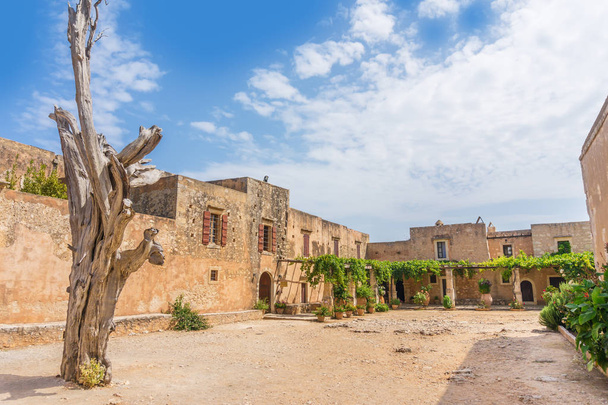 Arkadi Monastery inner yard with the old dead cypress tree with bullet holes at Crete, Greece. It was founded in the beginning of the 14th century and almost destructed by the Ottomans in 1866. - Foto, immagini