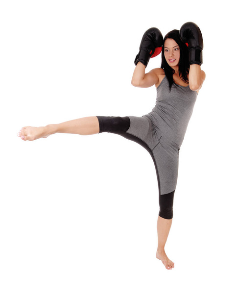 A slim young woman in exercising outfit praxis kick boxing with he - Foto, Imagen