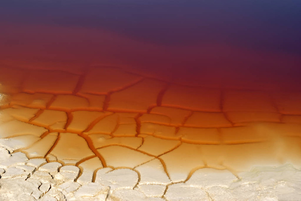 background - cracked clay shore of a reservoir with rusty water - Photo, Image