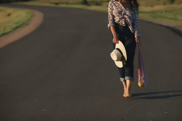 袋で美しい少女アスファルトの道路の上を歩く - 写真・画像