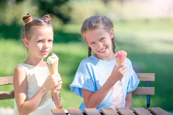 Niñas comiendo helado al aire libre en verano en la cafetería al aire libre
 - Foto, Imagen