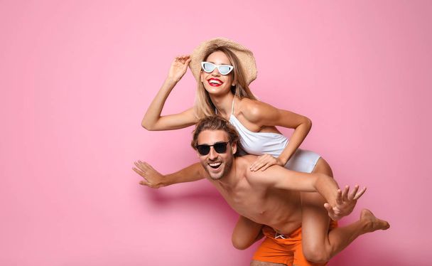 Happy young couple in beachwear on color background. Space for text - Фото, изображение