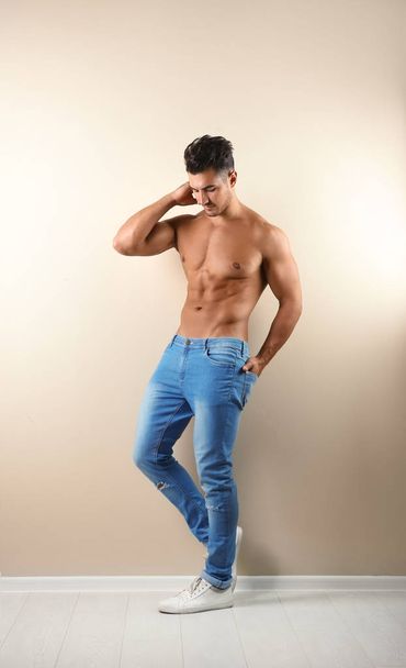 Shirtless young man in stylish jeans near light wall - Фото, изображение