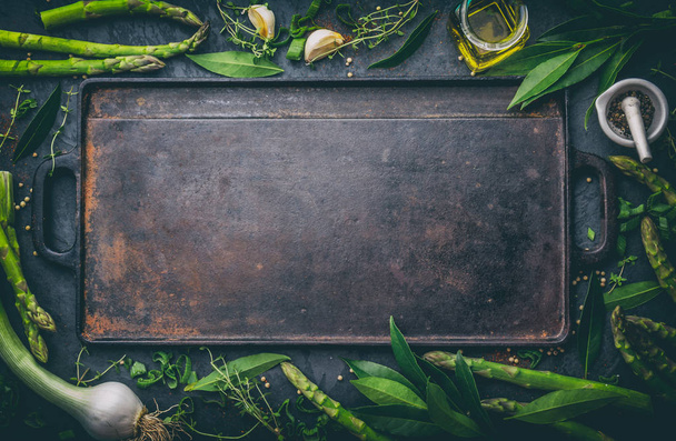 Food background with free space for text. Herbs, olive oil, spices around cast iron frying board. Top view. - Foto, imagen