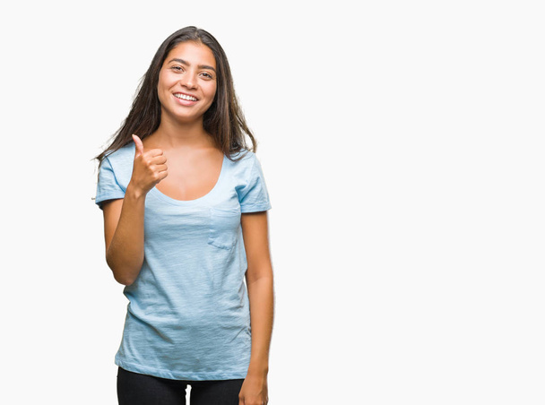 Young beautiful arab woman over isolated background doing happy thumbs up gesture with hand. Approving expression looking at the camera with showing success. - Photo, Image