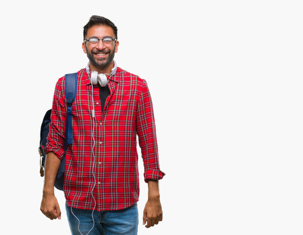 Homem estudante hispânico adulto usando fones de ouvido e mochila sobre fundo isolado com um sorriso feliz e legal no rosto. Pessoa com sorte
. - Foto, Imagem