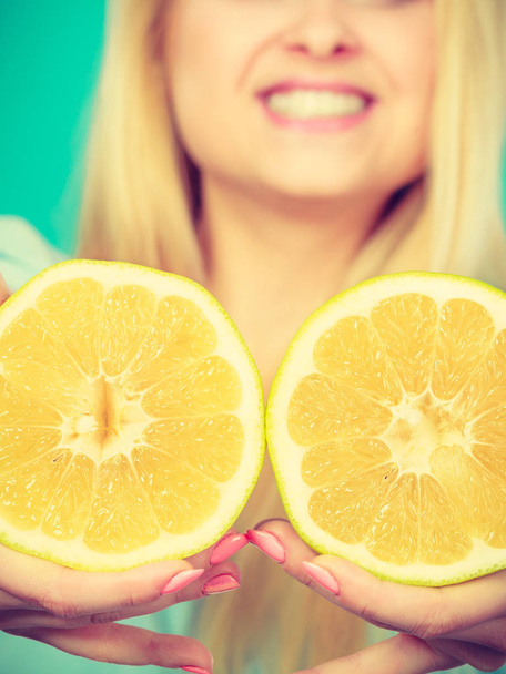 Woman smiling girl holding two halfs of yellow grapefruit citrus fruit in hands, on gren. Healthy food, dieting concept. - Foto, imagen