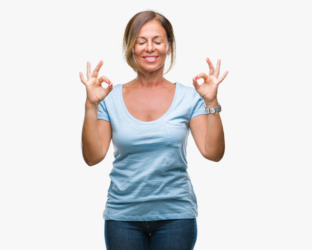 Μέση ηλικία ανώτερος Ισπανόφωνος γυναίκα πέρα από το απομονωμένο υπόβαθρο να χαλαρώσετε και χαμογελώντας με τα μάτια κλειστά να κάνει διαλογισμό κίνηση με τα δάχτυλα. Έννοια της γιόγκα. - Φωτογραφία, εικόνα