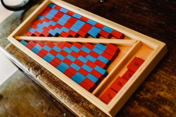 Gioco da imparare a contare, realizzato in legno blu e rosso, all'interno di un'aula montessori
. - Foto, immagini