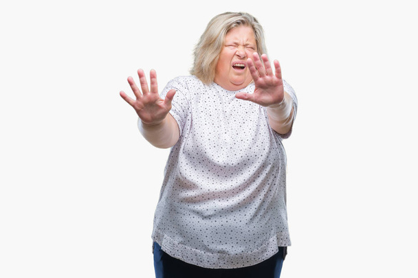 Senior plusz méretű kaukázusi nő több mint elszigetelt háttér fél, és retteg, félelem kifejezés stop gesztus a kezét, kiabált a sokk. Pánik koncepció. - Fotó, kép