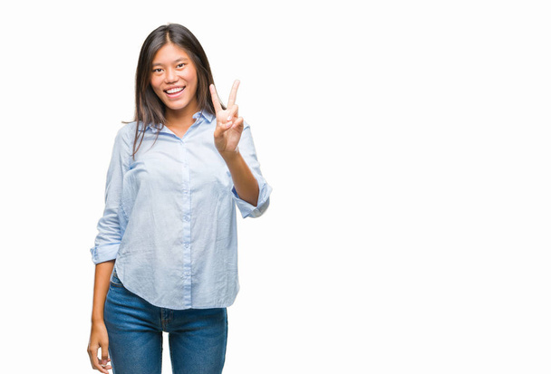 Jonge Aziatische zakenvrouw over geïsoleerde achtergrond glimlachend op zoek naar de camera vingers doen overwinning teken tonen. Nummer twee. - Foto, afbeelding
