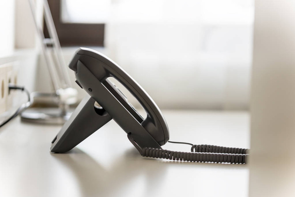 Teléfono fijo negro en escritorio de oficina blanco con fondo borroso
. - Foto, imagen