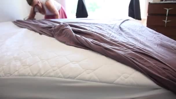 Γυναίκα ρίχνει ρυτιδωμένο μοβ φύλλα επάνω της queen size κρεβάτι σε μια βιασύνη, πάροδο του χρόνου - Πλάνα, βίντεο